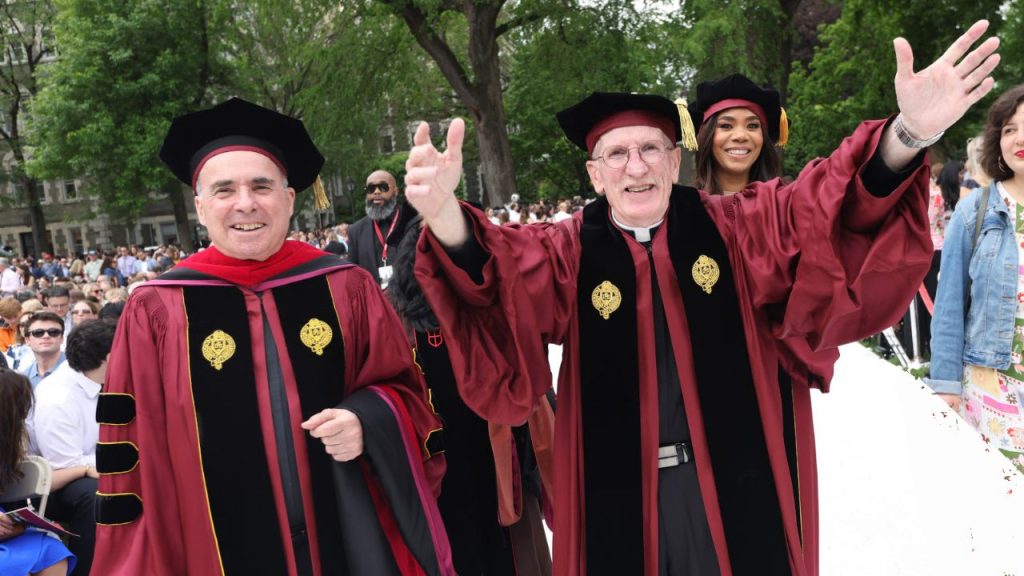 Father Joseph McShane walks down the aisle at Fordham's commencement with his arms outstretched. 