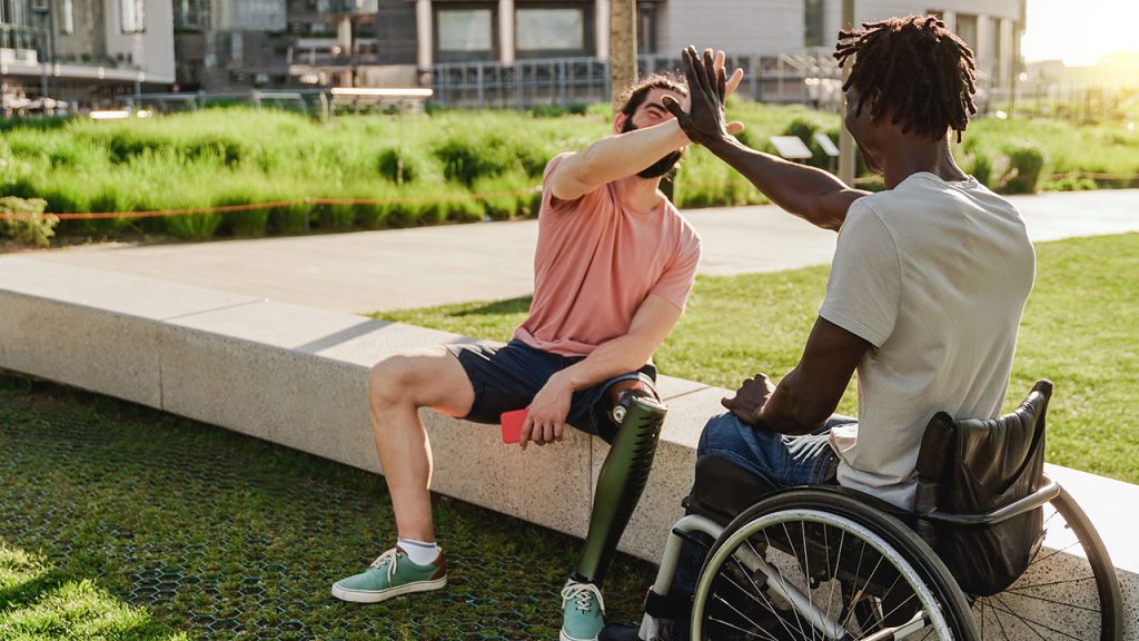 a man in a wheelchair high-fiving another man