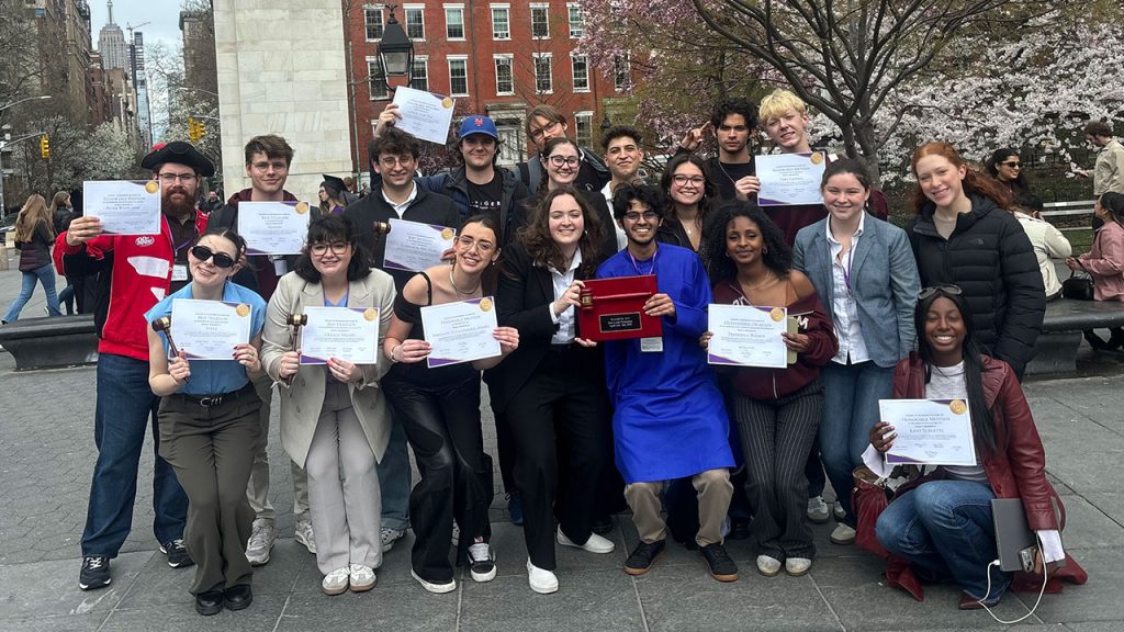 A group of happy students standing together holding up signs