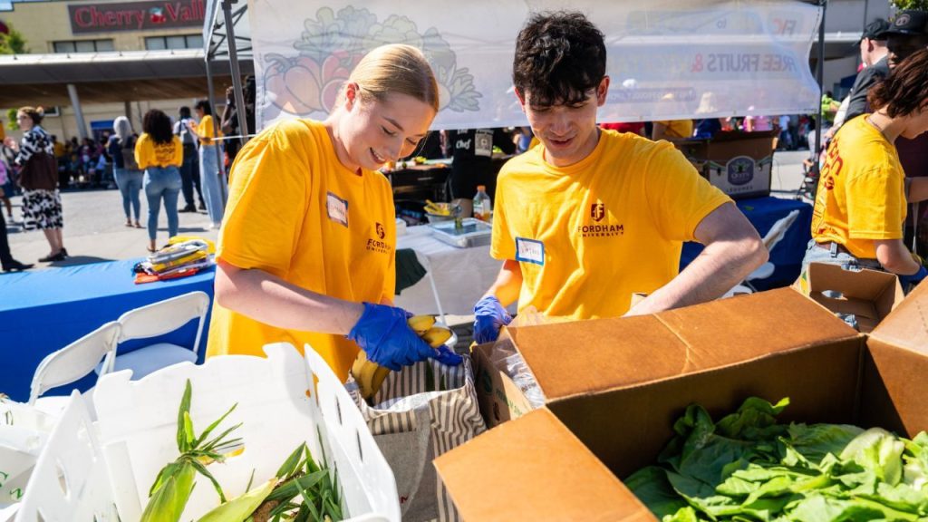 Two Fordham students sort through produce at a community market as part of Fordham's Urban Plunge.