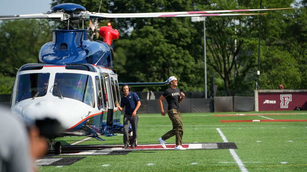 Tom Brady walking away from a helicopter parked on a football field