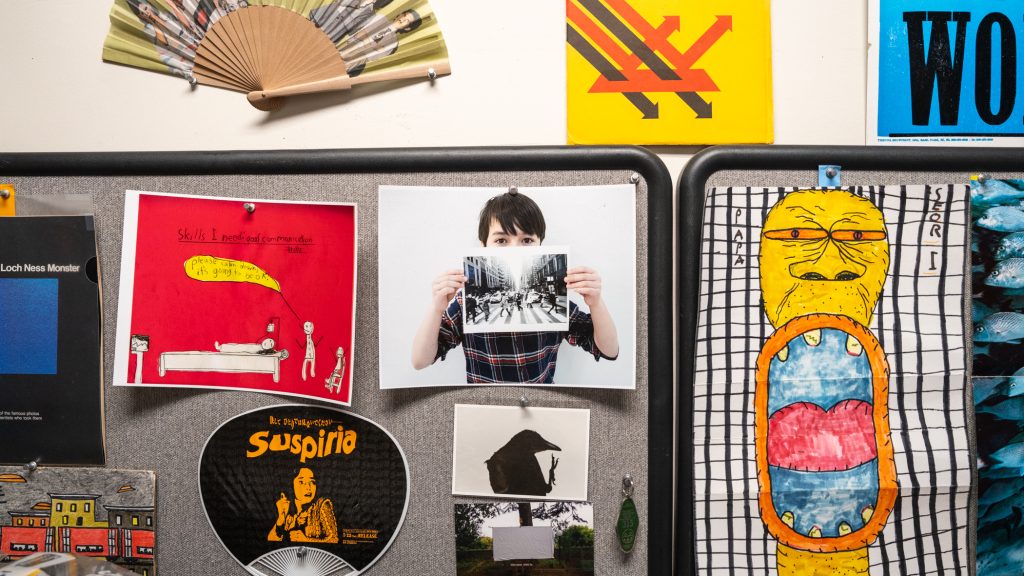 A wall with tacked drawings and pictures