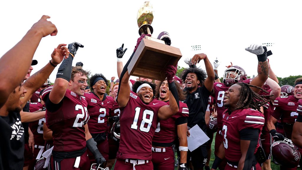 Football players celebrating while holding up a trophy.