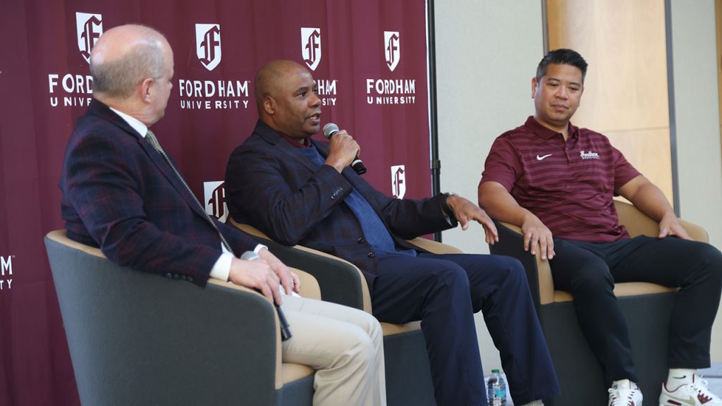 Three men sit on a panel
