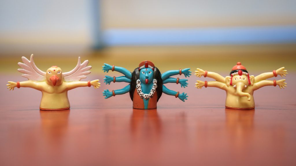 Three Hindu finger puppets on a desk