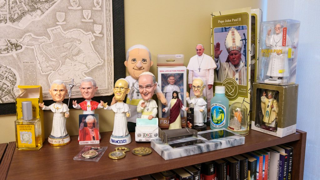 A collection of papal tchotchkes on a bookshelf