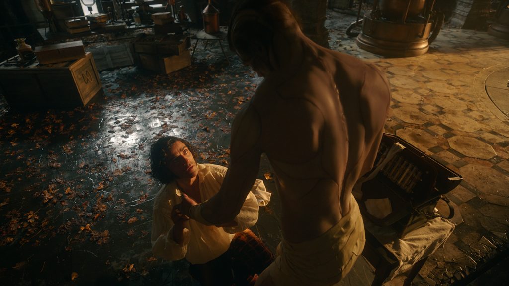 Victor Frankenstein, portrayed by Oscar Isaac, looking up at his creation, portrayed by Jacob Elordi